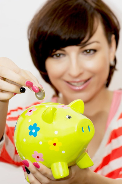 Young woman gives a euro coin into decorative ceramic piggy bank - Photo, Image