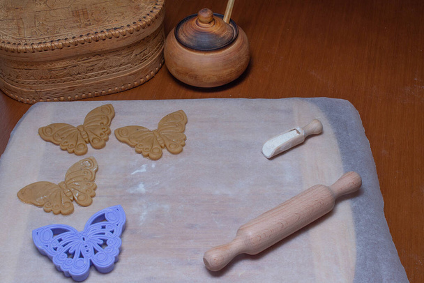 ダークテーブルの上で誕生日のためのジンジャーブレッド生地と蝶のクッキーカッター。料理クリスマスジンジャーブレッド. - 写真・画像