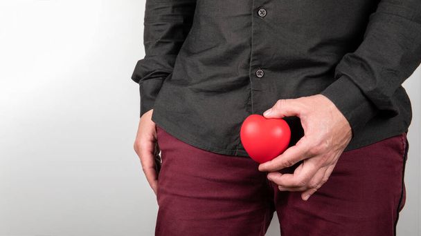 Male sexual health concept. Man holding heart at intimate parts. Urinating and prostate problems - Photo, Image