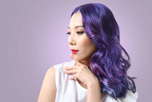 Schöne asiatische Frau mit ungewöhnlichen Haaren auf Farbhintergrund - Foto, Bild