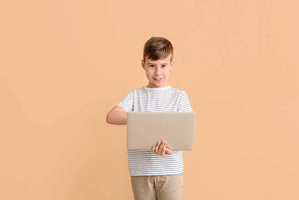 Netter Junge mit Laptop auf farbigem Hintergrund - Foto, Bild