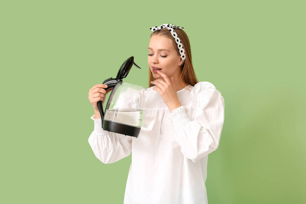 jonge vrouw houden elektrische waterkoker op kleur achtergrond - Foto, afbeelding