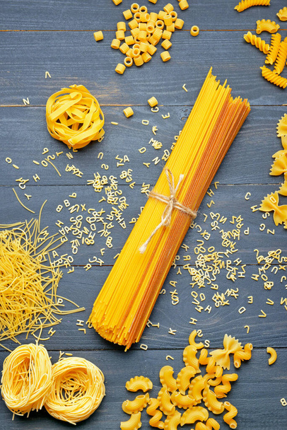 Composition of uncooked pasta on wooden background - Foto, afbeelding