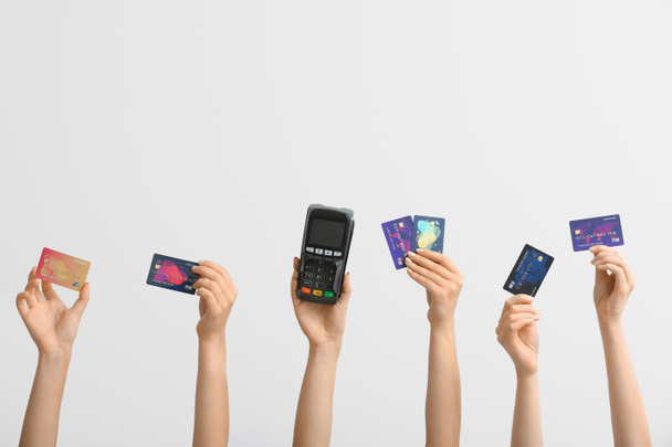 Vrouwelijke handen met creditcards en betaalterminal op witte achtergrond - Foto, afbeelding