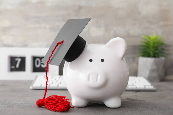 Piggy bank with graduation hat on table. Tuition fees concept - Photo, Image