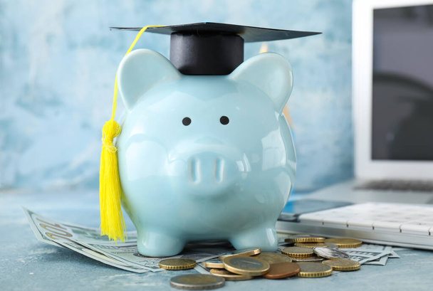 Tirelire avec chapeau de graduation et argent sur la table - Photo, image