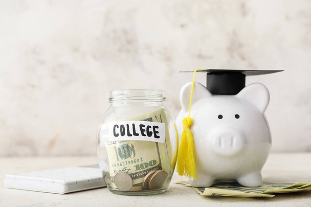Свинка в шляпе выпускника и банка с деньгами на образование на столе. Концепция оплаты обучения - Фото, изображение