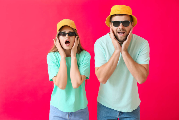 Surprised couple with stylish sunglasses on color background - Фото, зображення
