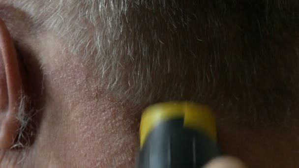 Corte de cabelo de um idoso sem-abrigo com um cortador especial. As mãos femininas cortam cabelos grisalhos de um homem vista de perto - Filmagem, Vídeo