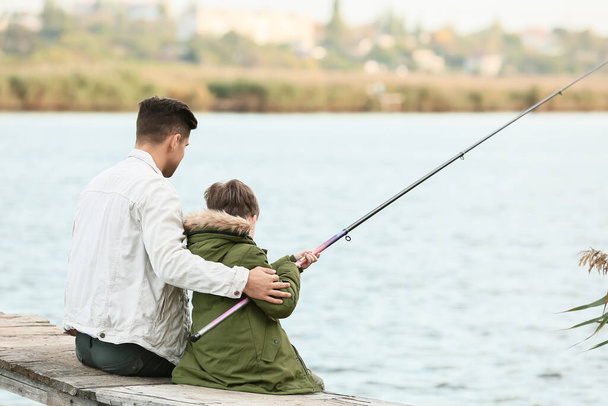 Küçük çocuk ve babası nehirde balık tutuyor. - Fotoğraf, Görsel