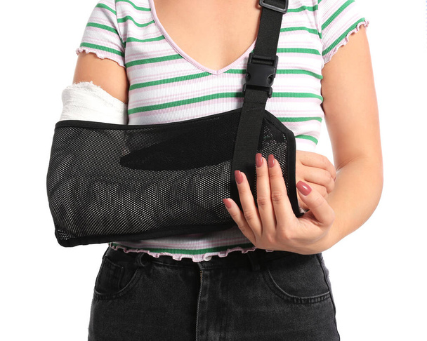 Giovane donna con braccio rotto su sfondo bianco - Foto, immagini