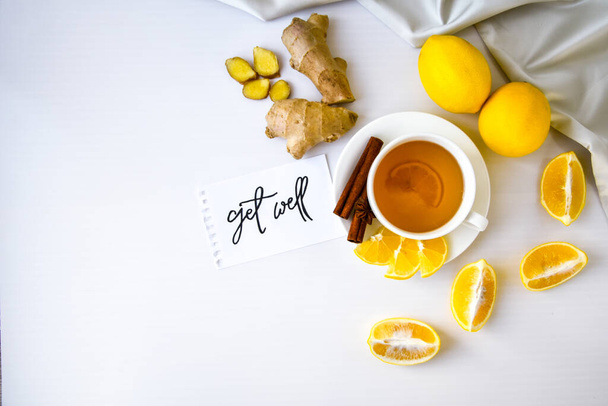 GET WELL - written on piece of paper among the products for the treatment of common cold - lemon, ginger, chamomile tea. Vitamin natural drink. Cinnamon anise star. - Foto, afbeelding