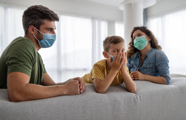 Young modern quarantined coronavirus family in medical masks at home - Photo, Image