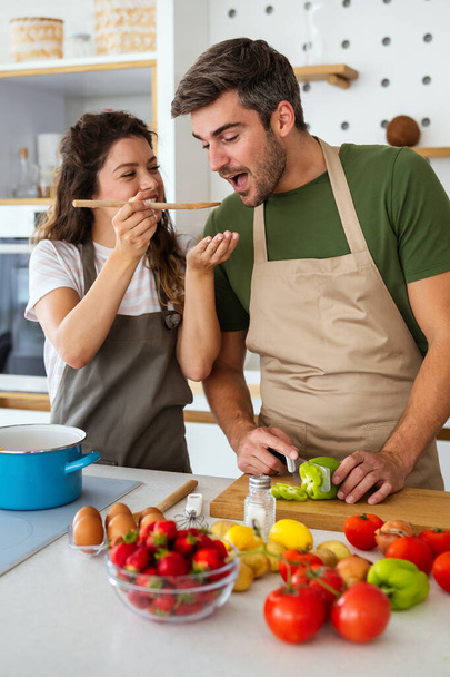 Happy young couple have fun in modern kitchen while preparing fresh vegetable food - Fotoğraf, Görsel