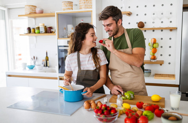 Happy young couple have fun in kitchen while preparing fresh organic food - Foto, Bild