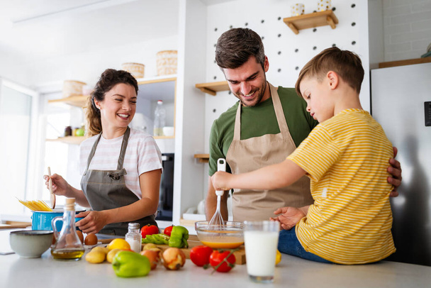 Happy young family preparing healthy food together in kitchen - Photo, image