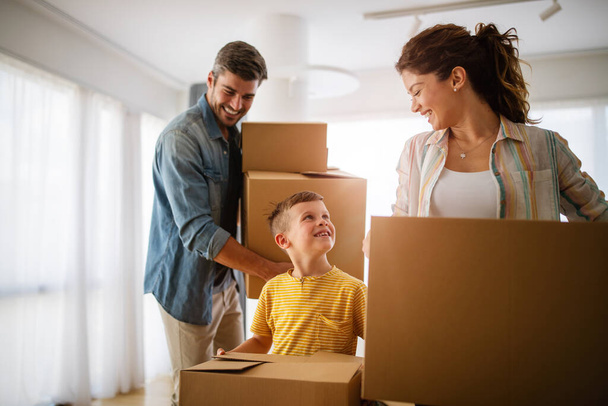 Happy family unpacking boxes in new home on moving day. People, real estate, new home concept - Foto, afbeelding