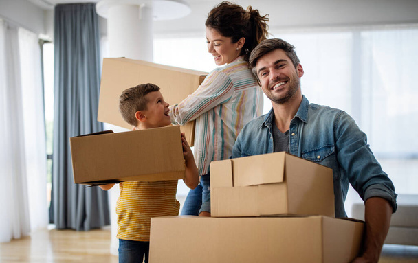 Happy young family unpacking cardboard boxes at new home. Moving in, new home people concept. - Zdjęcie, obraz