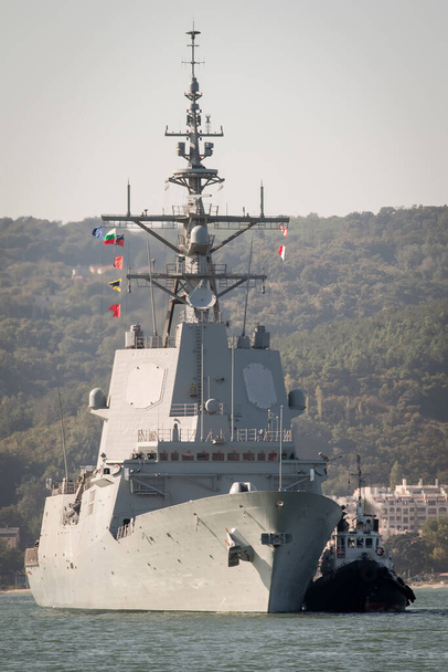 Буксир поддерживает военный корабль для стыковки в порту - Фото, изображение