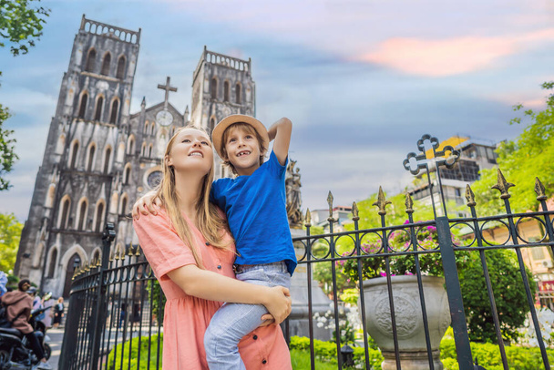 Young mom and son tourists on background of St Josephs Cathedral in Hanoi. Vietnam reopens after coronavirus quarantine COVID 19 - 写真・画像