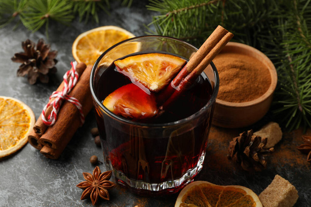 Glass of mulled wine and ingredients on black smokey background - Photo, image