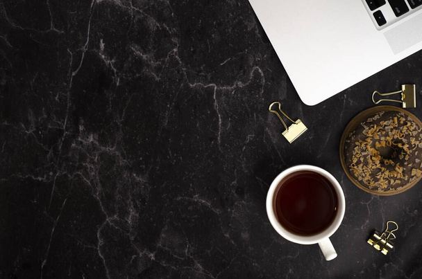 Black desktop flatlay mockup with laptop, cup of tea and donut - Photo, image
