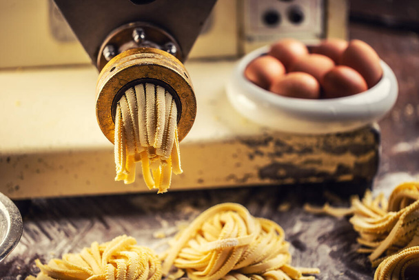 End of pasta making process with fresh fettuccine leaving the pasta maker. - 写真・画像
