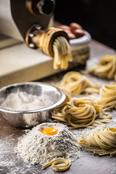新鮮なイタリアのフェットチーネを生産する小麦粉、卵、パスタメーカー.  - 写真・画像