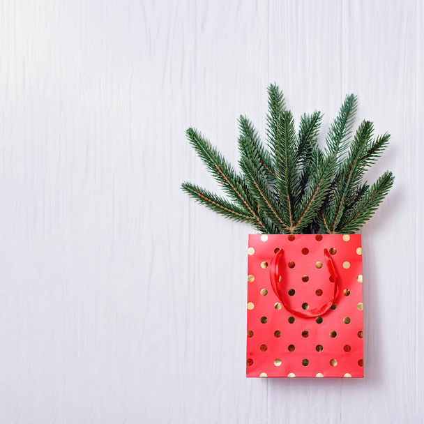 Christmas background. branches of an artificial pine in red with golden dots gift bag on white wooden background. Holiday background Happy New Year and Christmas. Copy space, Top view - Фото, изображение