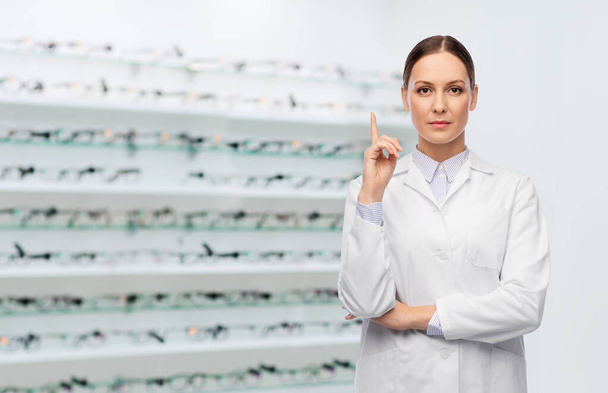 female doctor pointing finger up at optical store - Photo, Image