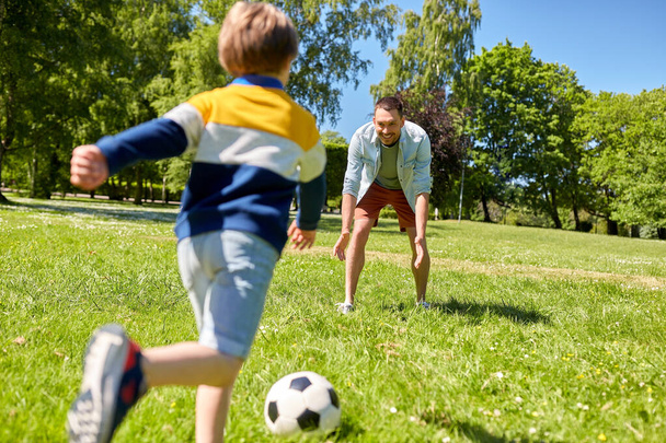 apa kisfiúval focizik a parkban - Fotó, kép