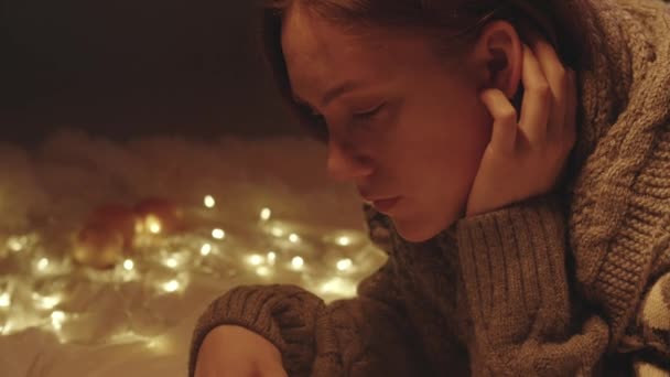 Πλάνα ανάγνωσης νεαρή γυναίκα σε πλεκτό πουλόβερ τρώει μανταρίνι - Πλάνα, βίντεο
