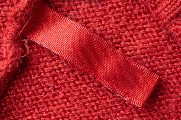 Leere Wäschepflegeetikett auf rotem Strickstoff Textur Hintergrund - Foto, Bild