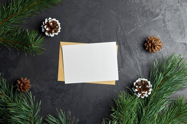 Christmas greeting card mockup with pine tree branches with cones on dark stony background. Christmas holidays flat lay, top view, copy space. - Foto, Imagem