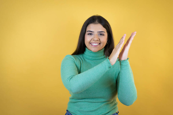 Fiatal kaukázusi nő izolált sárga háttér tapsol és tapsol boldog és örömteli, mosolygó büszke kezek együtt - Fotó, kép