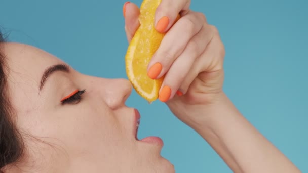 meisje probeert naar smaak een vrede van oranje in de studio - Video