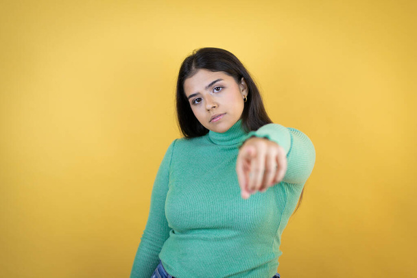 Young caucasian woman over isolated yellow background pointing to the front with finger - Photo, Image