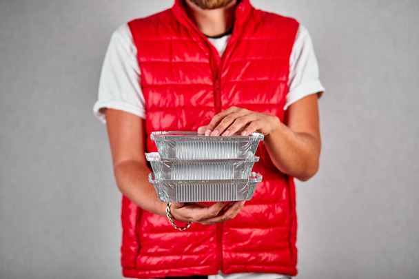 Delivery man in red vest uniform hold go box food, delivery service, isolated on grey background studio, Takeaway restaurants food delivery to home door, Service quarantine pandemic coronavirus, Contactless delivery. - Foto, imagen