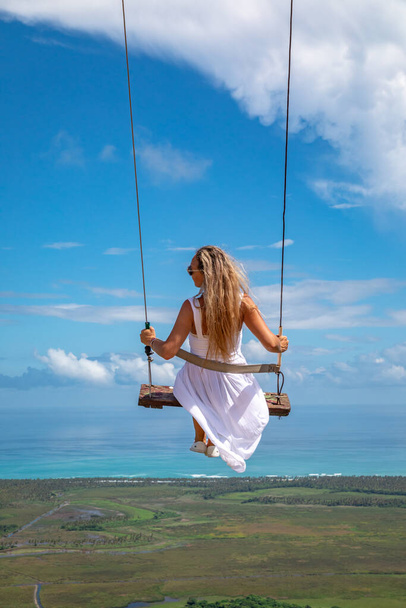 Woman swinging on swings over the green mountains with ocean sea caribbean tropical landscape and horizon line with blue sky. Montana Redonda, Dominican republic. - Foto, Imagem