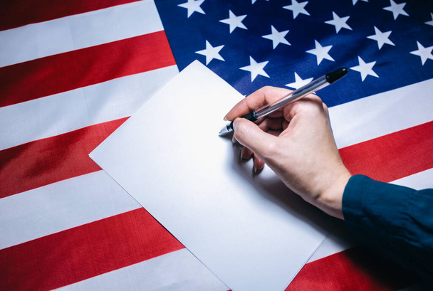American flag with dollars on it. Elections in the USA. Woman putting tick on the paper for vote. Political changes in the country. Copy space place. - Valokuva, kuva