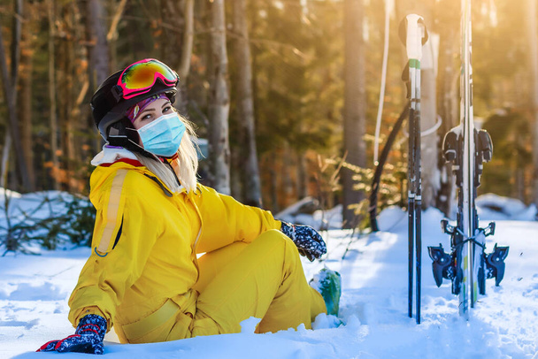 Frau mit medizinischer Maske während des Coronavirus COVID-19 an einem sonnigen Wintertag in einem Skigebiet - Foto, Bild