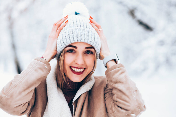 νεαρή γυναίκα φορώντας καπέλο στο χειμερινό χιονισμένο πάρκο - Φωτογραφία, εικόνα