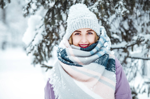 young woman in knitted hat smiling in  snowy park - Fotografie, Obrázek