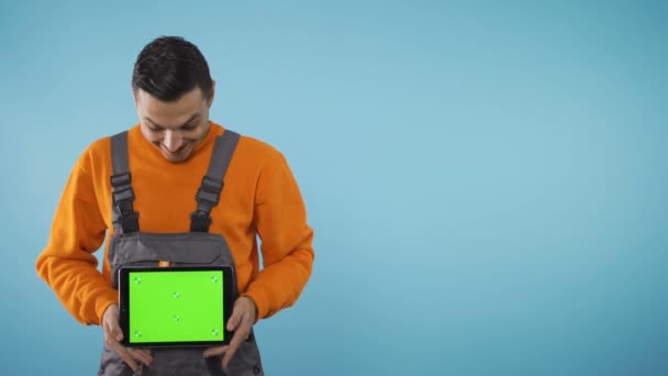 Innoissaan, onnellinen, ekstaattinen nuori mies teollisuuden työvaatteet tilalla tabletti ja tarkkailun vihreä ruutu - Materiaali, video