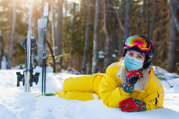 Orvosi maszkot viselő nő a COVID-19 koronavírus alatt egy napos téli napon egy sípályán - Fotó, kép