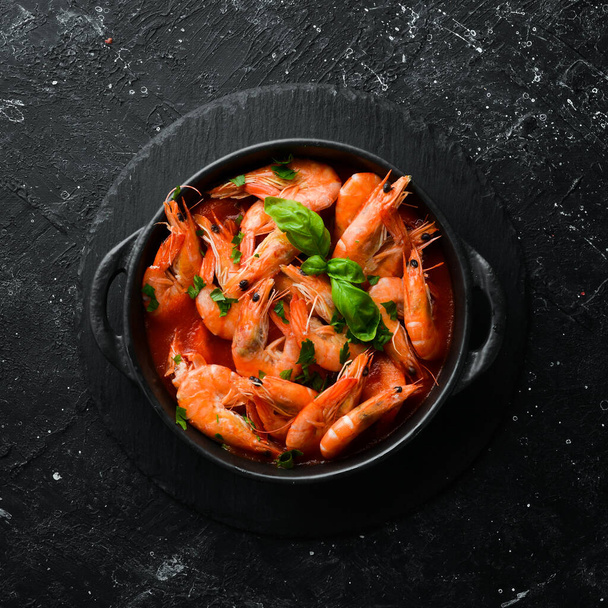 Food. Boiled shrimp in tomato sauce with basil on a black stone plate. Top view. Free space for your text. - Foto, imagen