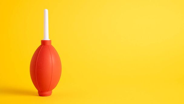 Izolovaný červený gumový vzduchový ventilátor pro čištění prachu z fotoaparátu a čočky na žlutém pozadí - Fotografie, Obrázek
