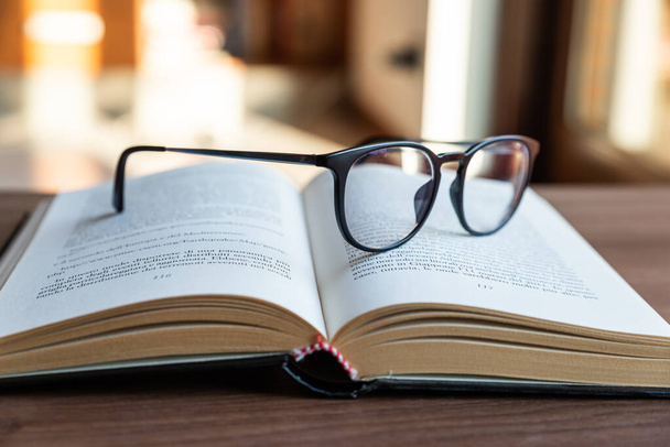 Open book, with eyeglasses on top - Photo, image