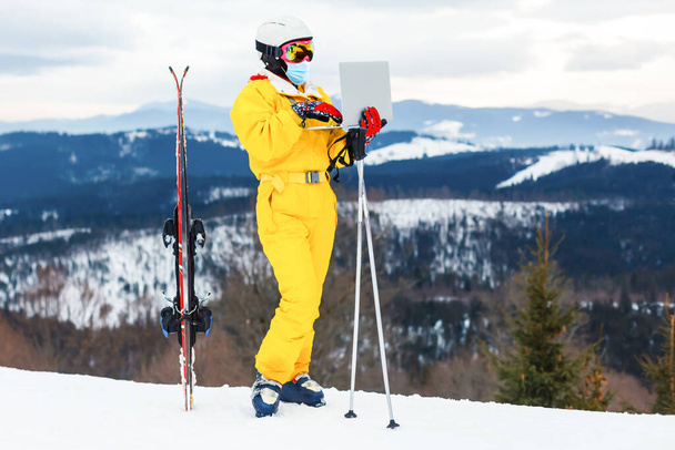 Mujer con máscara médica durante el coronavirus COVID-19 en un día soleado de invierno en una estación de esquí - Foto, imagen