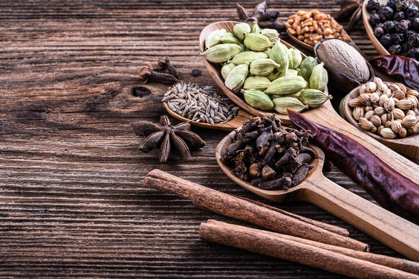 Different types of whole Indian spices in wooden background close-up.  Black pepper, fenugreek, anise, cinnamon, cardamom, nutmeg, clove, cumin. Healthy food - Fotó, kép